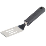 A FirmGrip spatula with a short, wide, slotted metal blade and black plastic handle featuring a hanging hole. The ergonomic spatula design and angled blade make lifting and flipping food easy.