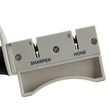 Close-up of a TableCraft FirmGrip Hand Held Sharpener with two slots labeled 1 SHARPEN and 2 HONE. The light gray, dishwasher safe sharpener features visible screws, black arrows for direction, and "TAIWAN" printed on the bottom right corner.
