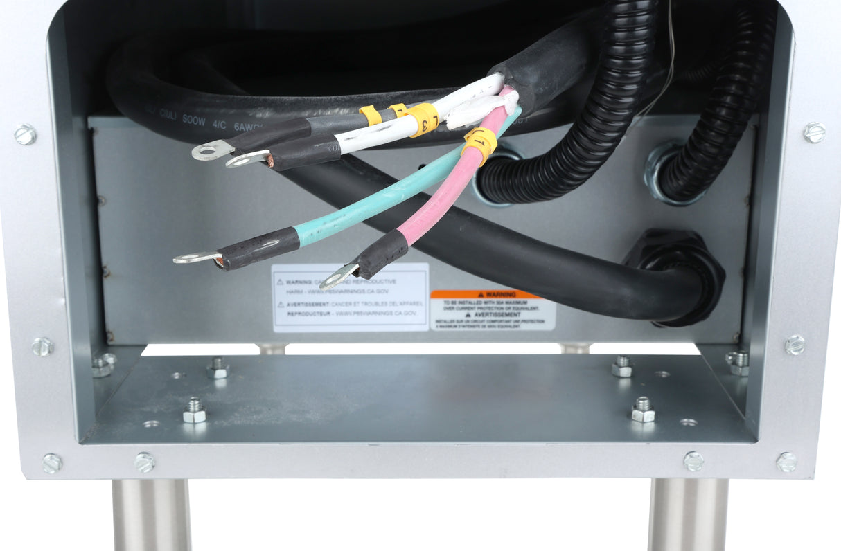 Close-up of an open metal control box on a commercial electric fryer, showing exposed black, white, pink, and green wires. Warning labels are visible inside the box, and cables enter through black grommets.