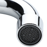 A close-up view of the end of a shiny, stainless chrome faucet shows the aerators honeycomb-like mesh pattern. The faucet curves downward, reflecting light on its metallic surface. The background is plain and out of focus.