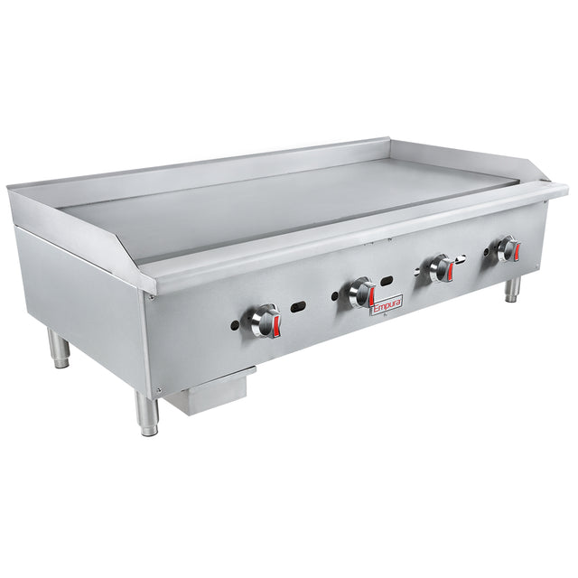 A large commercial stainless steel gas griddle with four control knobs, raised side and back edges, and sturdy legs. Designed for countertop installation in restaurant kitchens, it features a removable grease tray and branding on the front for heavy-duty use.