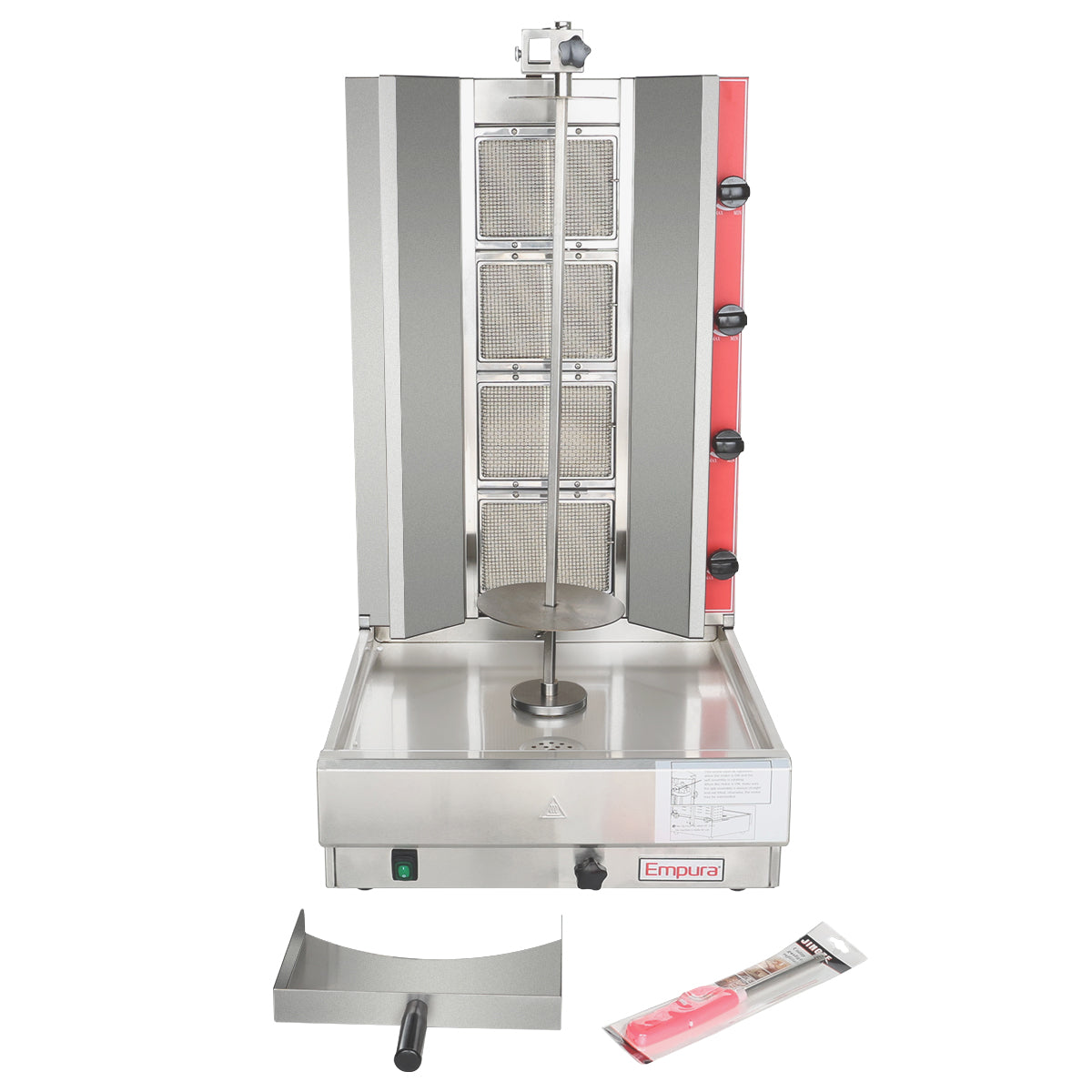 A vertical stainless steel gas broiler with a central rotating spit, four red control knobs on the right, a drip tray below, and accessories including a meat scoop and a knife in packaging placed in front of the machine.