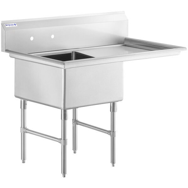 A 16 gauge stainless steel commercial sink features one square basin on the left, a right drainboard, a high backsplash with two faucet holes, and four sturdy legs. The design is utilitarian and industrial.