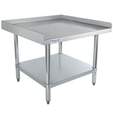 A stainless steel work table with NSF certification features a raised edge on three sides, a flat work surface, and a lower shelf. This Empura equipment stand has sturdy cylindrical legs, adjustable feet, and the brand logo on the front against a plain white background.