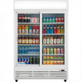 A commercial refrigerated merchandiser with glass sliding doors, stocked with assorted bottled and canned drinks including sodas, energy drinks, flavored teas, Gatorade, and water. The shelves are neatly arranged, and the fridge is clean and well-lit.