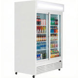 A refrigerated merchandiser on wheels with glass sliding doors displays assorted bottled and canned drinks—water, soda, energy drinks, juice, and sports drinks—arranged neatly on several shelves inside a well-lit, white fridge unit.