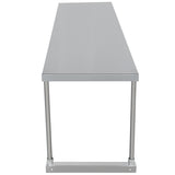 A long, rectangular stainless steel table with a smooth flat top and four cylindrical metal legs, seen from the short end. The minimalist industrial design could be enhanced with a table-mounted stainless steel overshelf.