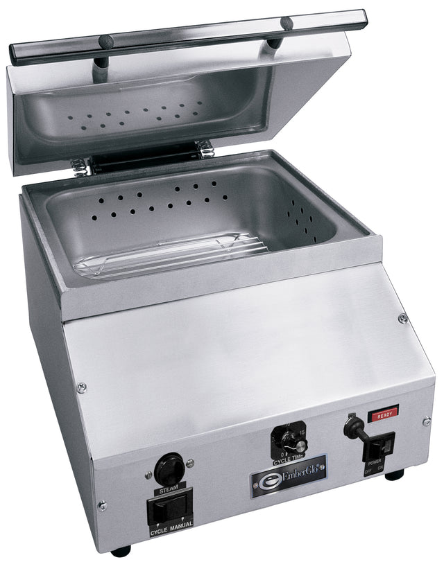 A commercial countertop steamer made of stainless steel, featuring a perforated tray and an upward-opening transparent lid. The front panel includes control knobs, switches, indicator lights, and labeled settings for cycle and steam functions.