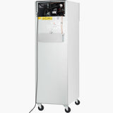 A tall, rectangular stainless steel refrigerator on four caster wheels features an open top section revealing electrical components, a yellow caution label, a closed middle compartment, and a black power cord hanging down the left side. The background is white.