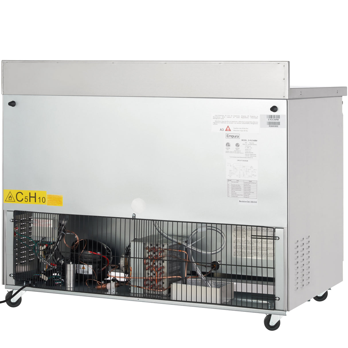 A commercial Empura E-KUC48W work top refrigerator with a metal exterior, vented lower section revealing internal coils and wiring, warning label “C5H10,” and wheels for mobility. The upper silver panel displays various labels and information stickers.