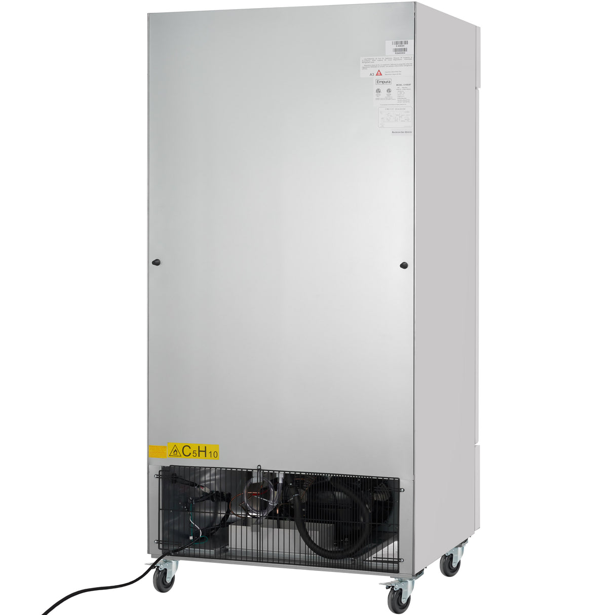 A large, upright commercial refrigerator with a plain silver front, ventilation and mechanical components visible at the bottom behind a black grille, four caster wheels for mobility, a yellow caution label on the lower left corner, and an electric cord extending out.