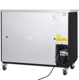 A large, stainless steel commercial machine on wheels with a vented section revealing mechanical parts at the lower right. There are warning labels, including a yellow one with C5H10 for isopentane gas. A power cord extends from the bottom.