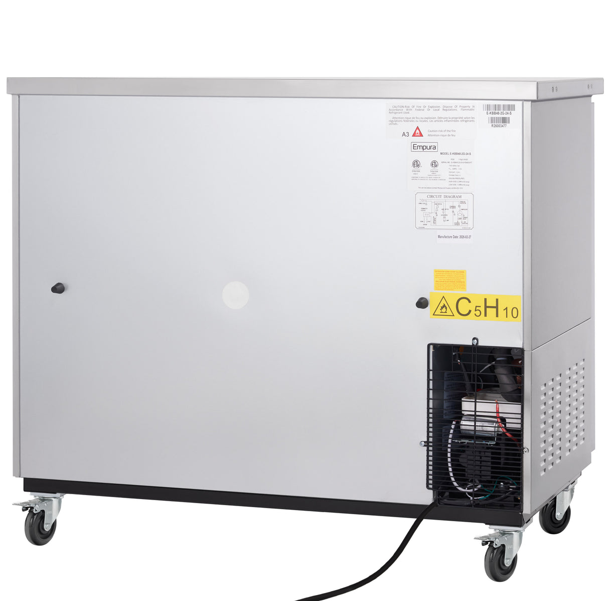 A large, silver, rectangular commercial refrigerator on four wheels, with labels and warning signs on the front. The lower right side features a vented compartment exposing black tubing and wiring. A black power cord extends from the unit.