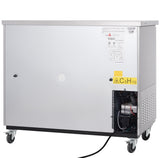 A large, silver, rectangular commercial refrigerator on four wheels, with labels and warning signs on the front. The lower right side features a vented compartment exposing black tubing and wiring. A black power cord extends from the unit.