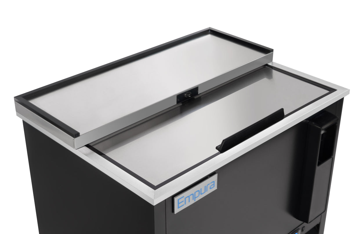 A close-up of a black bottle cooler or commercial refrigeration unit with a sliding stainless steel top lid, partially open. The front displays an Empura label. The rectangular sliding door cooler features a side handle for easy access.
