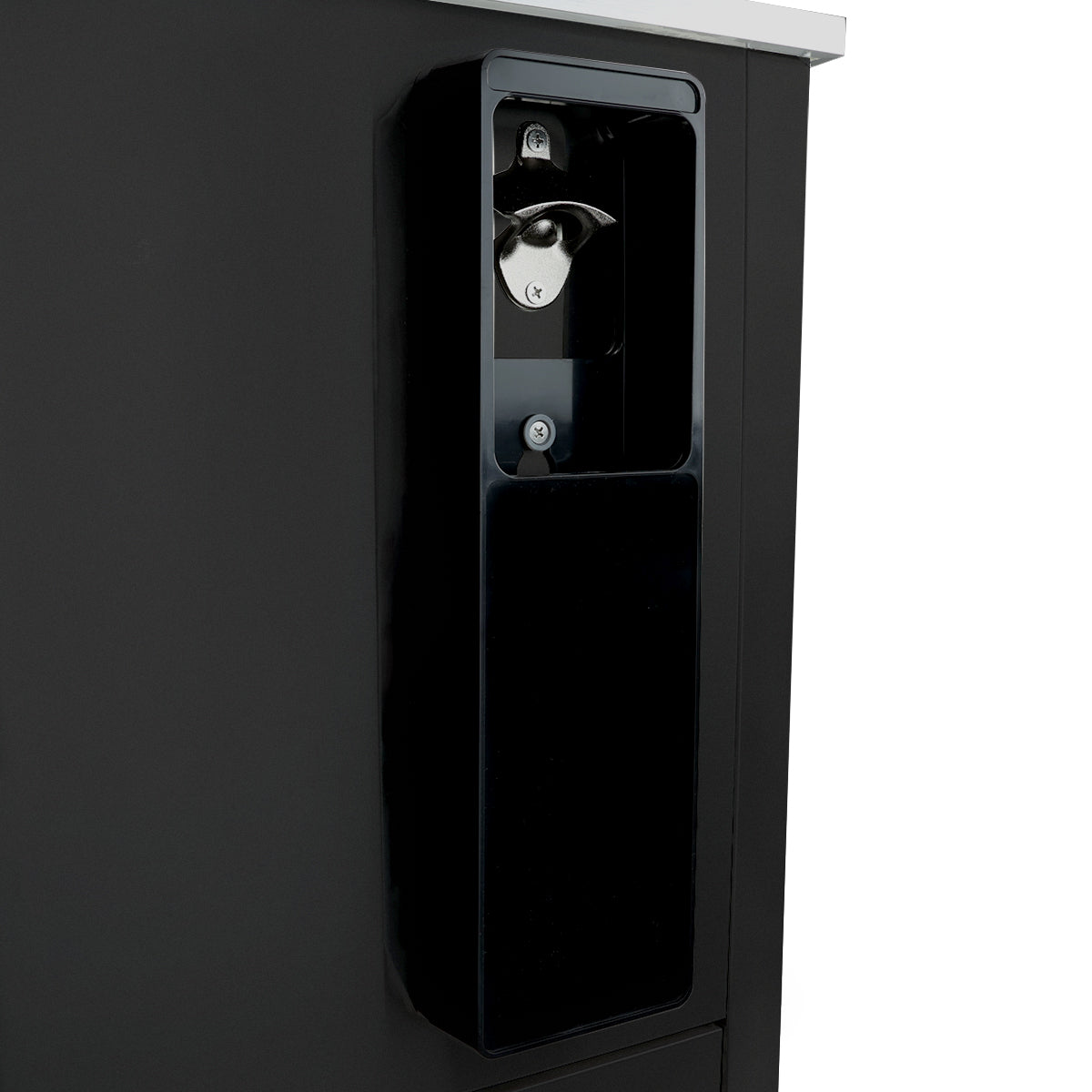A close-up of a black bottle opener and cap catcher mounted on the side of a bottle cooler, with a metal opener at the top and a rectangular container below to catch caps. The background is plain and uncluttered.