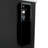 A close-up of a black bottle opener and cap catcher mounted on the side of a bottle cooler, with a metal opener at the top and a rectangular container below to catch caps. The background is plain and uncluttered.