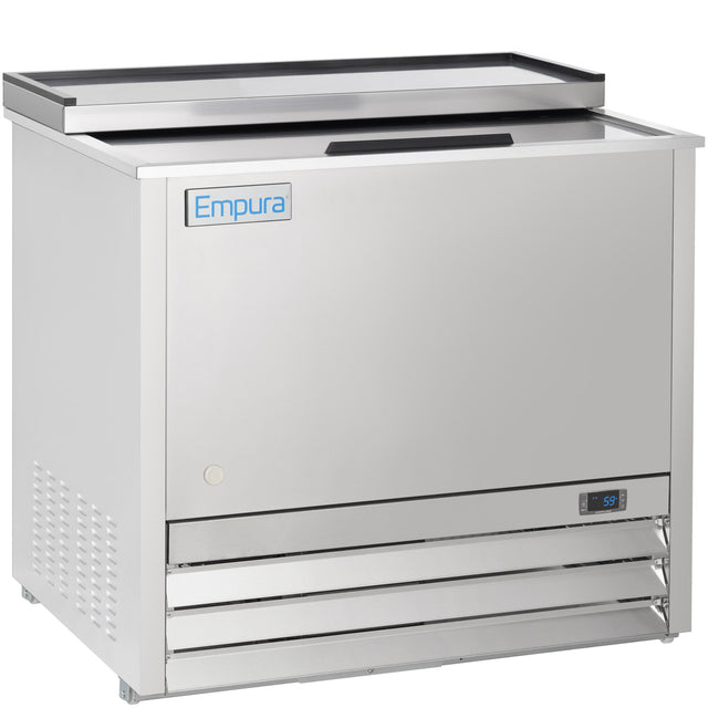 A stainless steel Empura refrigeration commercial bottle cooler features a top sliding lid, digital temperature display, metal label on the front, and bottom right ventilation grilles. Its reflective surface and clean, modern lines highlight premium commercial freezer quality.