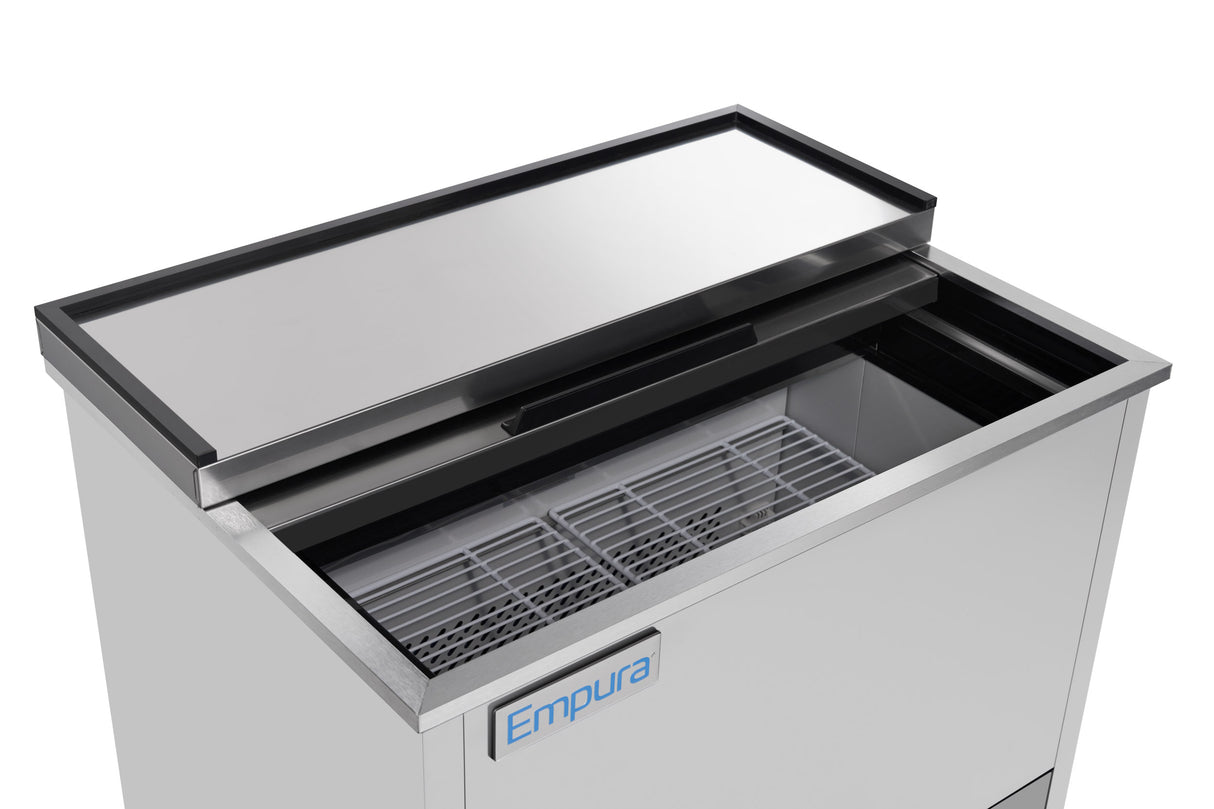 A stainless steel Empura refrigeration ice bin with a sliding lid, partially open to reveal a metal wire rack inside. The front displays a blue Empura logo. The bin has a clean, modern appearance and is designed for storing ice.