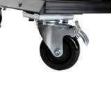 Close-up of a black swivel caster wheel with a metal bracket and foot-operated locking mechanism, attached to the bottom corner of a beer dispenser cart with dual tap tower, shown against a plain white background.