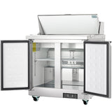 A commercial stainless steel refrigerated sandwich prep table with double doors open reveals clean shelves and compartments. The top lid is also raised, and the unit—a product of Empura refrigeration—features wheels and a digital control panel at the bottom.
