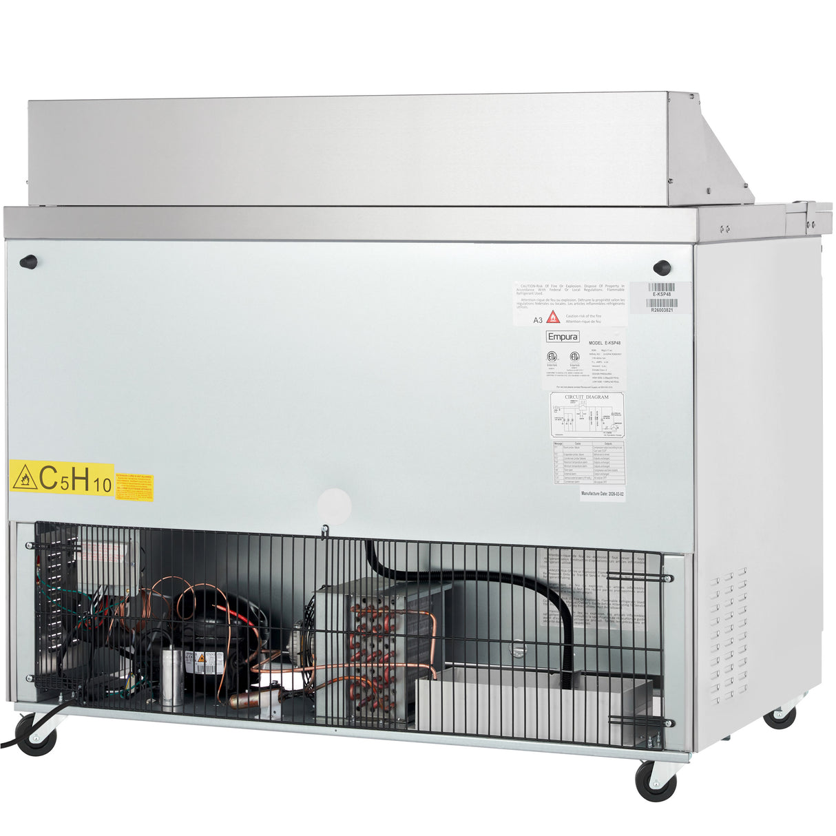 A commercial ice machine on wheels with a large silver body, similar to an Empura refrigeration unit. The lower front panel is open, revealing components like coils and a compressor. A yellow warning label reads C5H10, and product stickers are on the front.