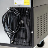 A close-up of the lower side of a black Empura Refrigeration machine shows a coiled power cord, vented metal panels, and internal components visible through a mesh cover. A yellow warning label about fire risk is attached near the top.
