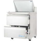 A stainless steel Empura refrigeration mega top prep table on wheels with two open front drawers. The top features a closed compartment with a hinged lid and food prep area. The Empura label is visible on the lower drawer.