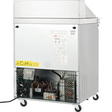 An Empura refrigeration unit on wheels with a white exterior. The bottom front panel is open, showing wiring, coils, and components. A C5H10 label and warning signs are visible. This refrigerated sandwich prep table sits on caster wheels for easy mobility.