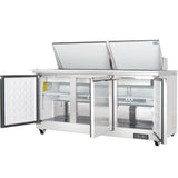 A commercial stainless steel salad prep table with two top lids open showcases the workspace. Below, three compartment doors reveal empty cooling shelves. This refrigerated sandwich prep table stands on casters for mobility in any commercial kitchen refrigeration setup.