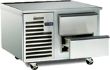 A stainless steel commercial refrigerator with self-contained refrigeration sits on wheels, featuring two horizontal pull-out drawers—one partially open—and a vented section with a Traulsen logo. The appliance is clean, industrial, and ideal as a freezer equipment stand.