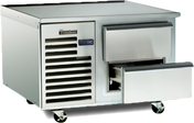 A stainless steel commercial refrigerator with self-contained refrigeration sits on wheels, featuring two horizontal pull-out drawers—one partially open—and a vented section with a Traulsen logo. The appliance is clean, industrial, and ideal as a freezer equipment stand.