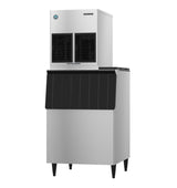A high production ice machine with a stainless steel body, black front panel, and four legs. The top unit has two black vents, while the lower ice storage bin features a slanted, textured black door for an industrial and modern look.