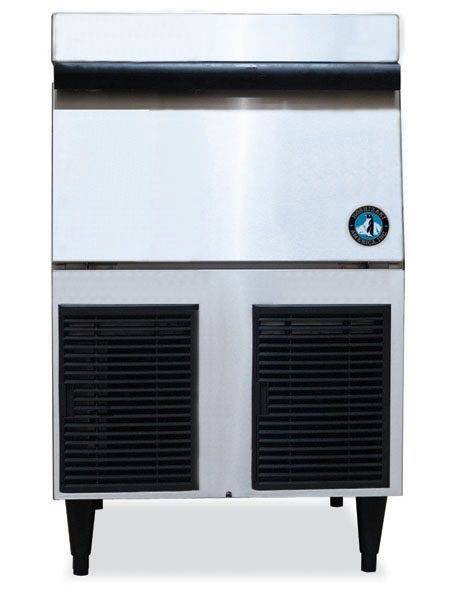 A commercial ice maker with a stainless steel exterior, front-facing air vents at the bottom, black legs, and a round logo on the upper right side. This self-contained condenser machine produces cubelet ice and is shown against a plain white background.