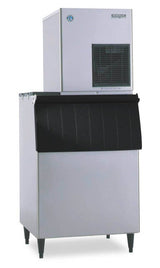 A commercial ice machine with a large stainless steel body, black vented panel on the upper front, and a black pull-down door below. This air-cooled ice maker stands on four legs and features a boxy, utilitarian design for industrial or food service use.