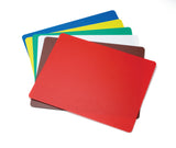 A set of six flexible rectangular plastic cutting mats, each a different color—red, brown, blue, green, yellow, and white—are fanned out on a white background. These dishwasher safe mats stack neatly with the red one on top.