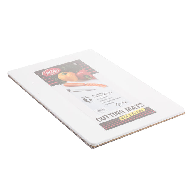 A white polyethylene cutting mat is shown still in its packaging. The label features images of a knife, tomato, and onion, and notes it is dishwasher safe. The rectangular mat measures 6 in x 9 in and lies flat on a white surface.