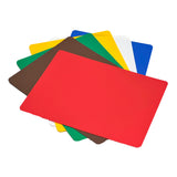 Seven flexible rectangular cutting boards in red, brown, green, yellow, white, blue, and a second green are stacked in a fanned arrangement, with the red board on top. These dishwasher safe boards are displayed on a white background.