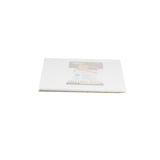 A white flexible cutting mat made of polyethylene is packaged in clear plastic, lying flat on a white background. A label with a sliced apple is visible. The mat appears new, unused, and is likely dishwasher safe for easy cleaning.