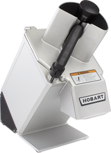 A stainless steel Hobart Food Processor with a slanted design, large black handle, and dual feed tubes. Featuring continuous feed capability, vented sides, and a warning label on the front, its sturdy metallic finish ensures reliable performance.