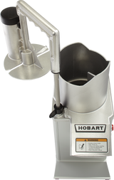 A commercial Hobart food processor with a large stainless steel feed chute, handle, and safety guard. The machine is silver with a visible Hobart logo and yellow warning label. The image is taken from above, showing the open chute.