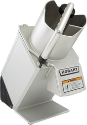 A metallic Hobart FP150 Food Processor with a large continuous feed chute, pusher handle, and warning label. Angled to the left, it displays both its side and front, featuring the branded Hobart label above the caution notice.