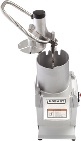 A Hobart FP250-1 Food Processor with a cylindrical metal chamber, safety handle, and continuous feed pusher attachment. The silver machine displays the Hobart logo and a warning label on the front, shown from an elevated angle.