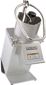 A commercial food processor with a stainless steel body, labeled “Hobart.” It features a large cylindrical feed tube for continuous feed, a pusher handle, and a safety warning label. The device is angled, highlighting its sturdy, industrial design.