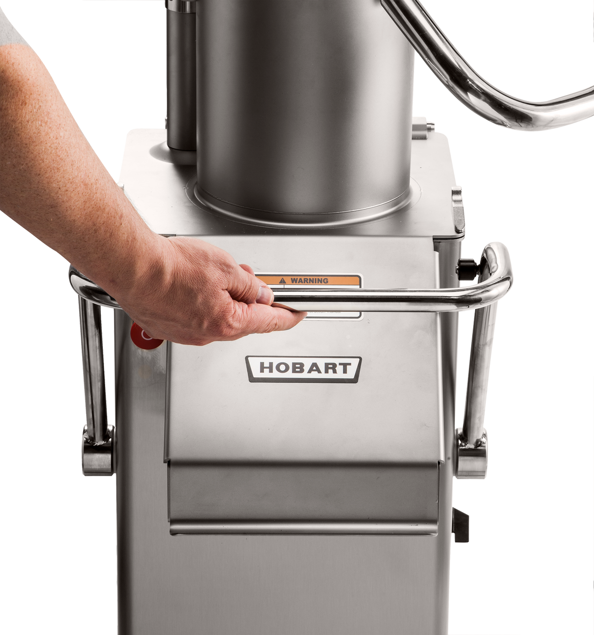 A hand grips a metal handle on a stainless steel Hobart FP400I Continuous-Feed Food Processor. The 132 lb/minute machine displays the Hobart logo and a yellow warning label. Part of a person’s arm and gray shirt are visible on the left.