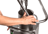 A close-up of a persons hand gripping the metal handle of a Hobart FP400I-1 Continuous-Feed Food Processor, made of stainless steel with cylindrical and tubular components, designed for 132 lb/minute production against a plain white background.