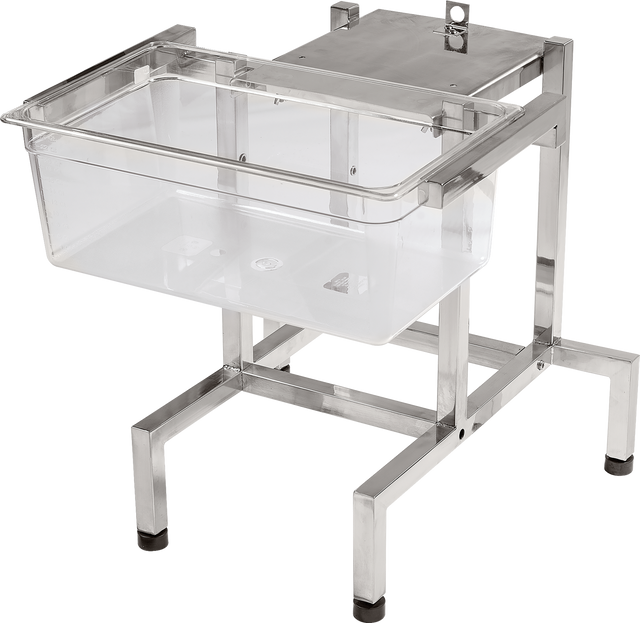 A transparent plastic infant bassinet rests on a sturdy, rectangular stainless steel frame with an FP100 mount at one end. The frame features rubber pads on the feet for stability. The bassinet is empty, set against a plain white background.