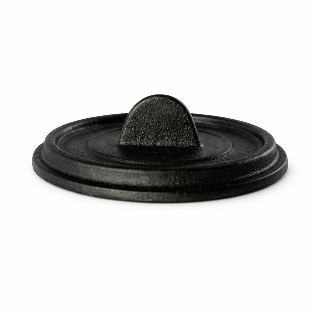A round, black FortaLite Mini Cassolette lid with a flat top and small, arched handle in the center. The slightly textured cast aluminum surface is photographed on a white background, highlighting its sturdy, minimalist design.
