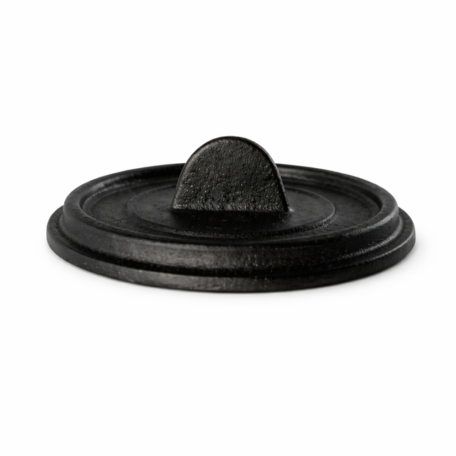 A round, black FortaLite Mini Cassolette lid with a flat top and small, arched handle in the center. The slightly textured cast aluminum surface is photographed on a white background, highlighting its sturdy, minimalist design.
