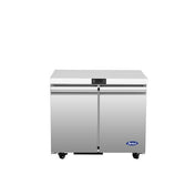 A stainless steel Atosa USA undercounter refrigerator with two doors, black handles, and four small caster wheels. The design is modern and industrial, featuring a blue Arctic Air logo on the smooth front surface.